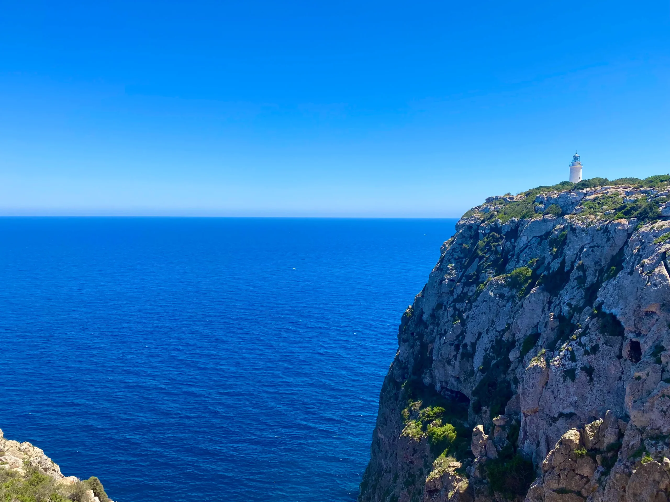 Panoramic view from El Pilar de la Mola in Formentera, showing the sea horizon and the lighthouse on the cliff
